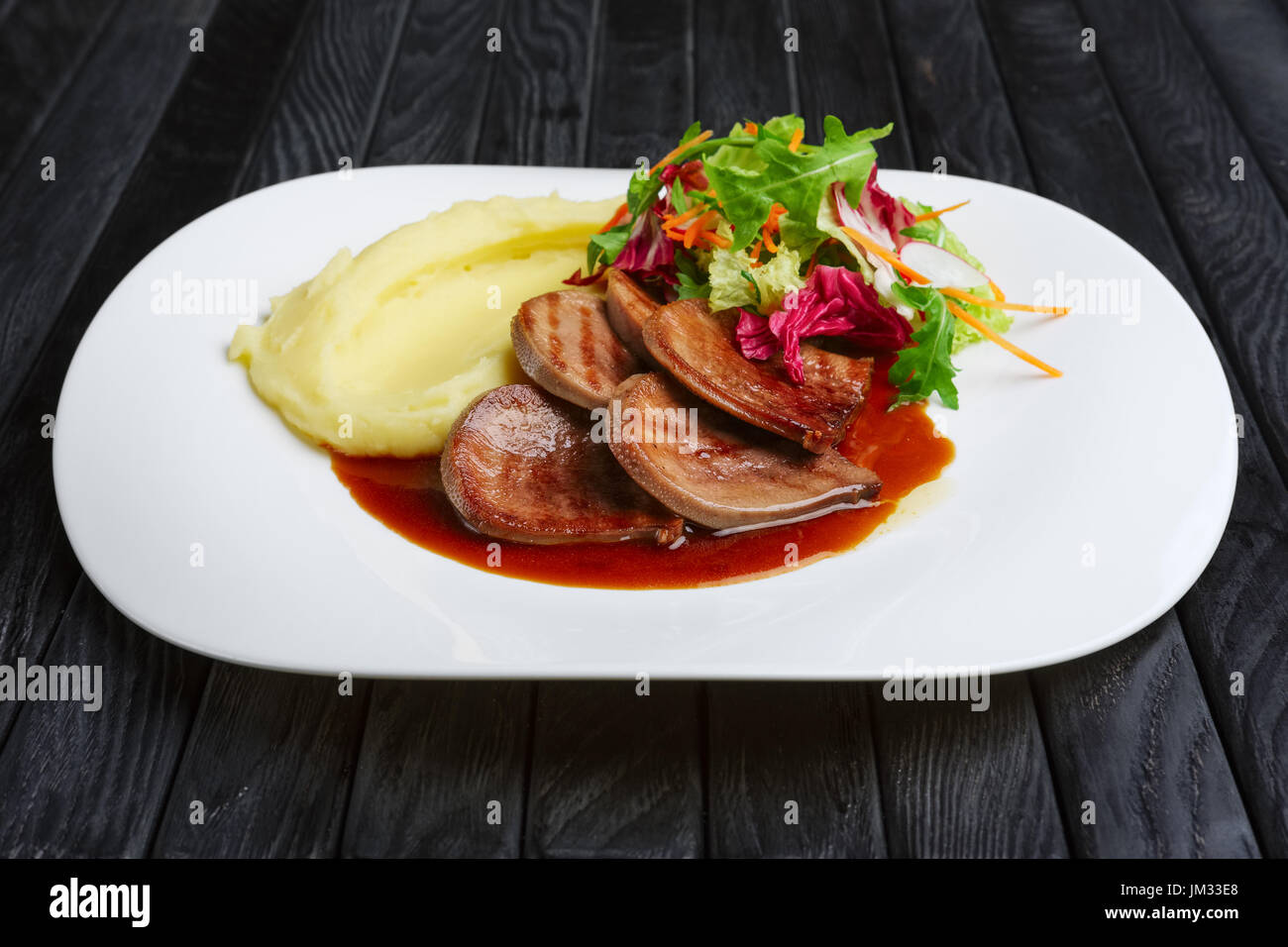 La langue de boeuf avec purée de pommes de terre et salade avec sauce aux airelles Banque D'Images