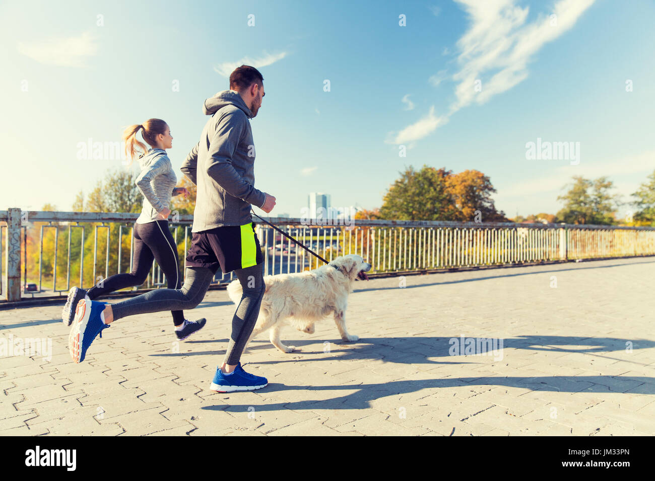 Heureux couple avec chien qui court à l'extérieur Banque D'Images