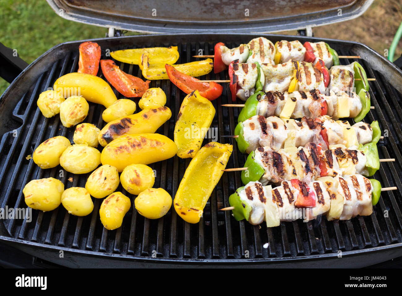 Un assortiment de grillades de viande avec légumes sur les braises d'un barbecue, close-up. Banque D'Images