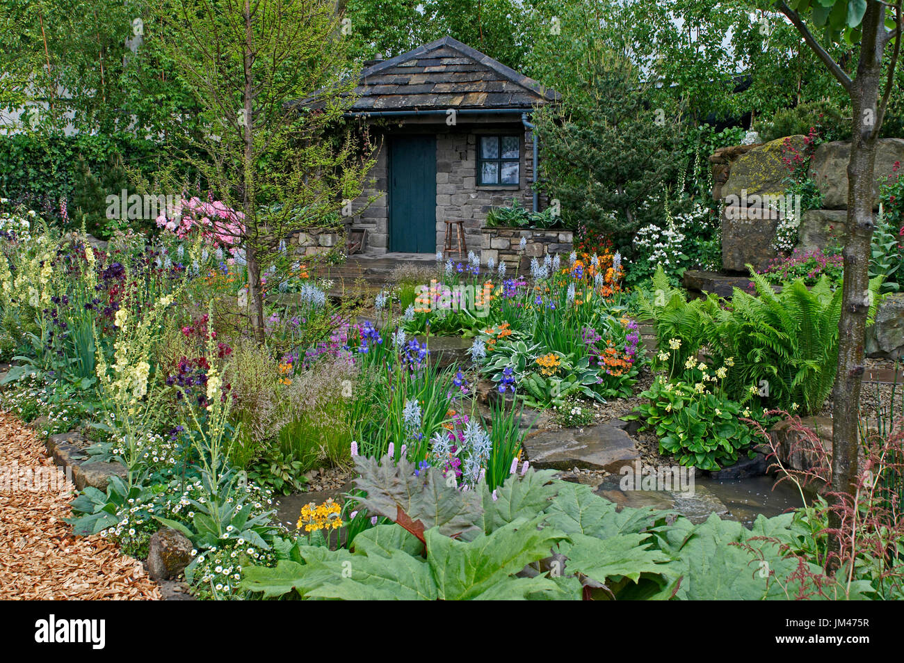 Un chalet et jardin situé dans un bois de rocaille avec un affichage coloré de fleurs Banque D'Images