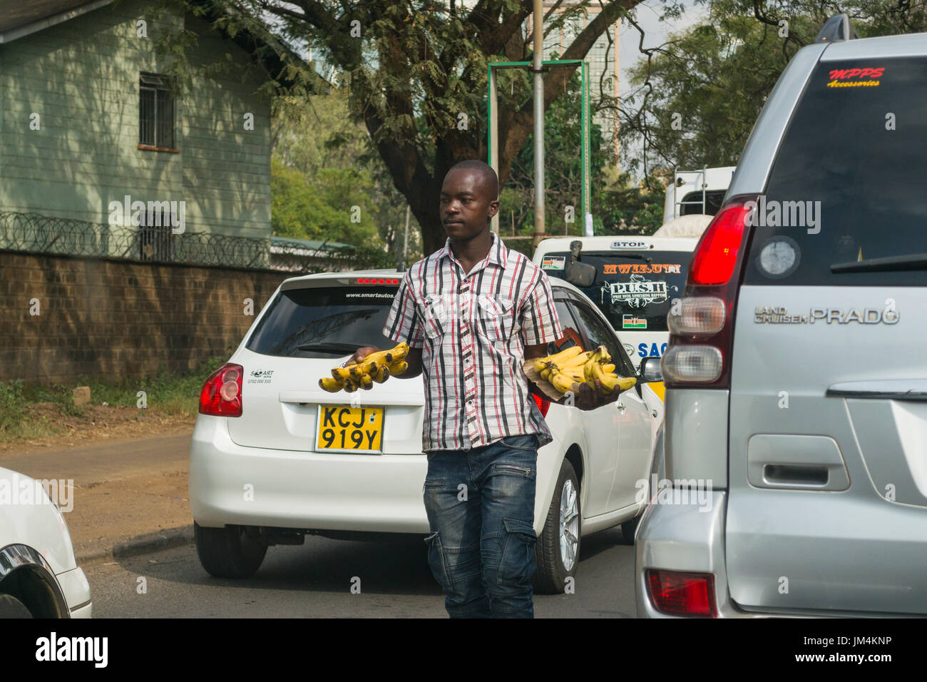 Un homme offrant les bananes en vente aux conducteurs dans les embouteillages sur l'autoroute Uhuru à Nairobi, Kenya Banque D'Images