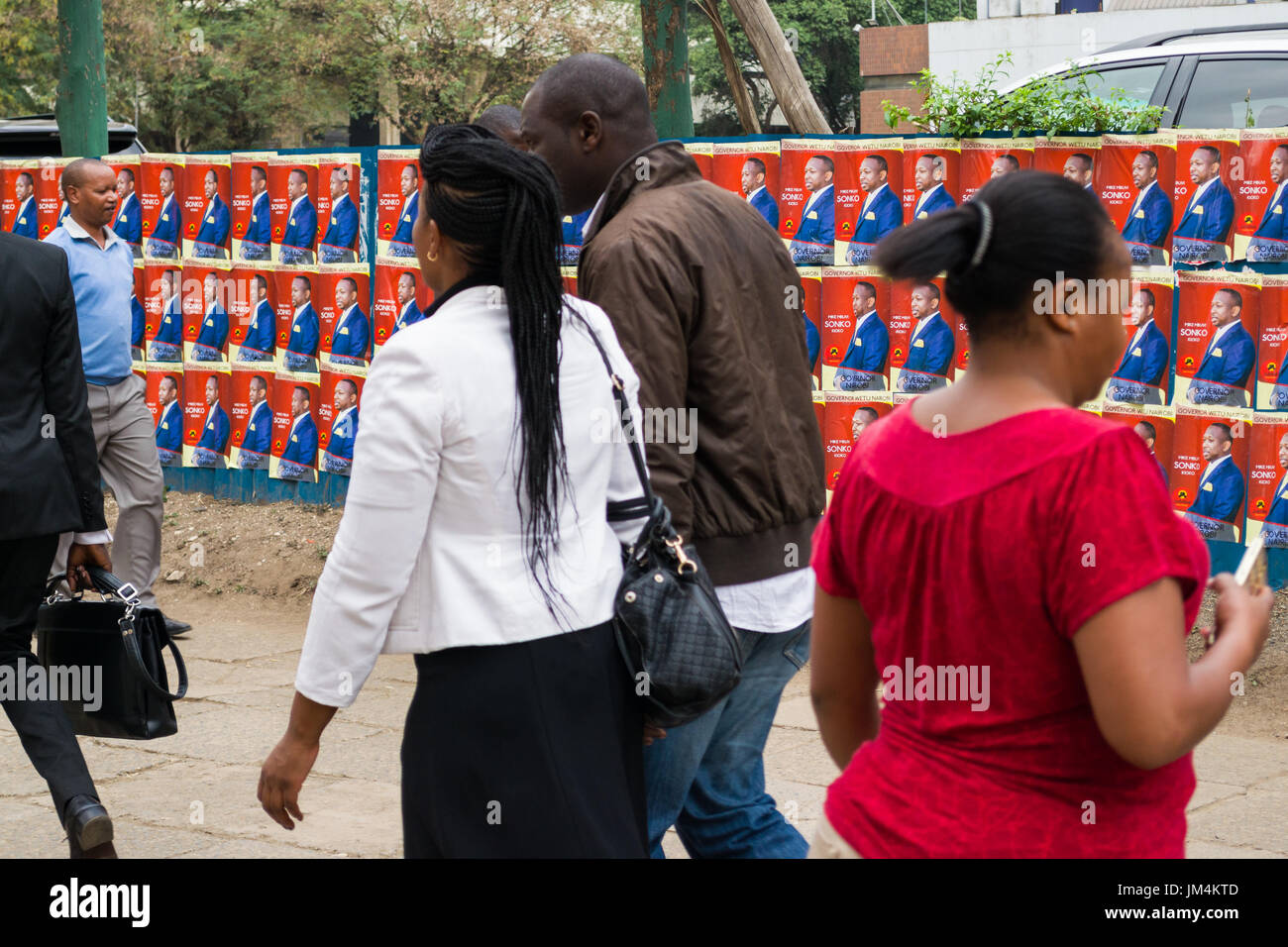 Les gens en passant devant les affiches des candidats à l'élection de Kenyan sur mur dans la ville de Nairobi, Kenya Banque D'Images