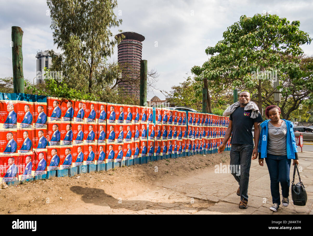 Les gens en passant devant les affiches des candidats à l'élection du Kenya à Nairobi sur le mur avec la Ville Dubai International Convention Centre en arrière-plan, au Kenya Banque D'Images