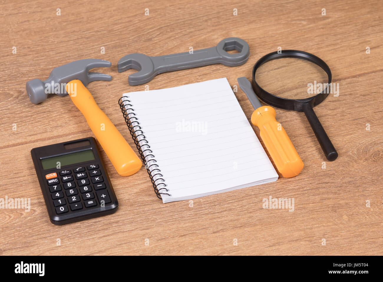 Passage vue rapprochée sur plusieurs outils jouet en plastique et bloc-notes et calculatrice et loupe sur table en bois Banque D'Images