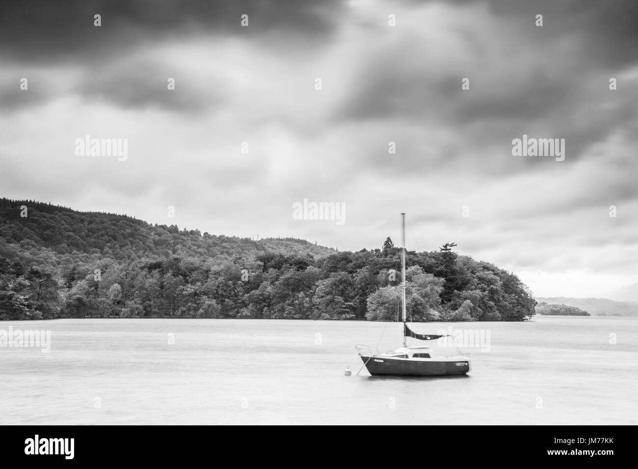 Un bateau à voile dans un lac calme que Storm s'approche. UK Banque D'Images