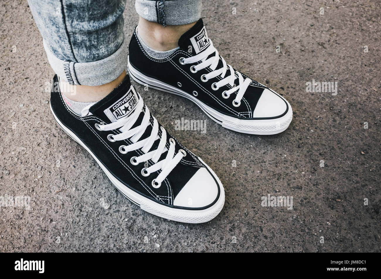 Saint-pétersbourg, Russie - 30 mai 2017 : les pieds dans une paire de toile noir Chuck Taylor All-Stars chaussures occasionnels sur route asphaltée. Banque D'Images