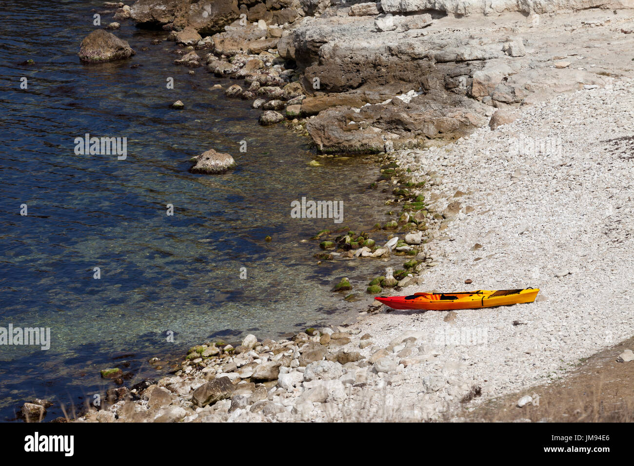 Kayak Orange sur une plage de galets de la côte de la mer au soleil Journée d'été. Vue de dessus. Banque D'Images