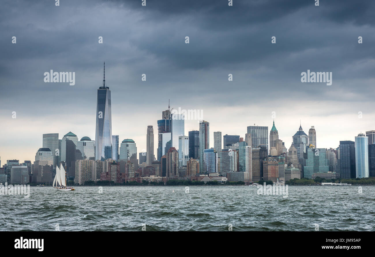 Les nuages de tempête tonitruant sombre linceul sur le Lower Manhattan skyline et un petit yacht à voile sur la rivière Hudson à New York, New York, USA Banque D'Images