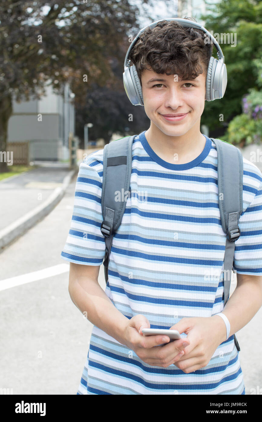 Portrait of Teenage Student à l'extérieur du bâtiment du collège d'écouter de la musique Banque D'Images