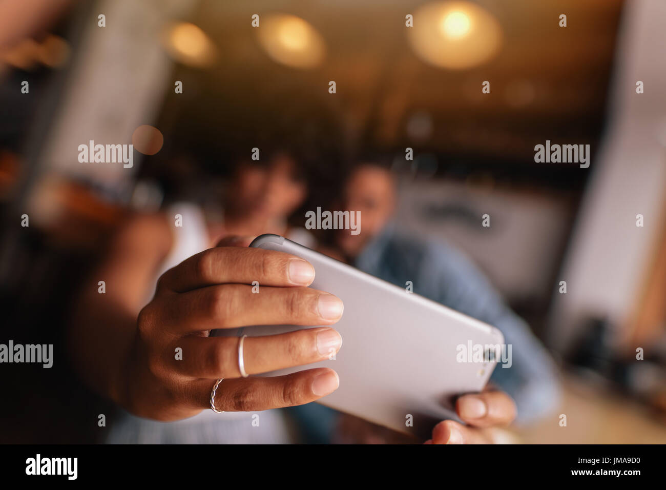 Close up of female hands holding smart phone et prenant. selfies Jeune femme en tenant avec selfies téléphone mobile alors qu'il était assis au café avec son petit ami. Banque D'Images
