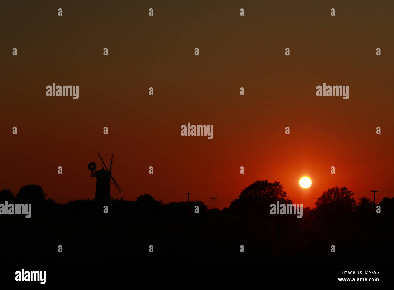 Great Bircham, UK. Le 25 juillet, 2017. Le ciel devient orange comme le soleil se couche derrière Bircham windmill à Norfolk. Bircham Mill a été construit en 1846, mais dans les années 20, les voiles ont été supprimés et la tour a été abandonné, mais maintenant c'est un moulin entièrement restauré et de travail Bircham windmill in Great Bircham, Norfolk le 25 juillet 2017 Crédit : Paul Marriott/Alamy Live News Banque D'Images