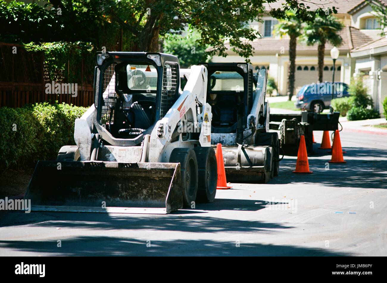 Une ligne de front end loader véhicules de construction est garé près d'une route, avec des cônes de signalisation orange, au cours de la construction routière et de réfection du projet dans la région de la baie de San Francisco suburb de San Ramon, Californie, le 26 juin 2017. Banque D'Images