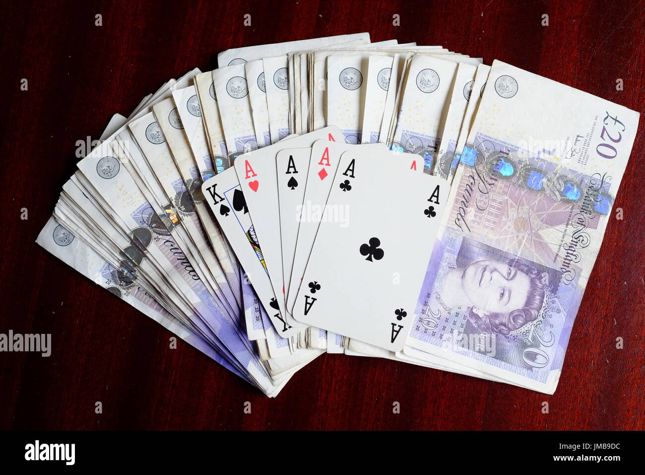 Quatre As et un roi, une main de poker gagnante de la chance et une fortune en £20 notes sur un tableau sombre Banque D'Images