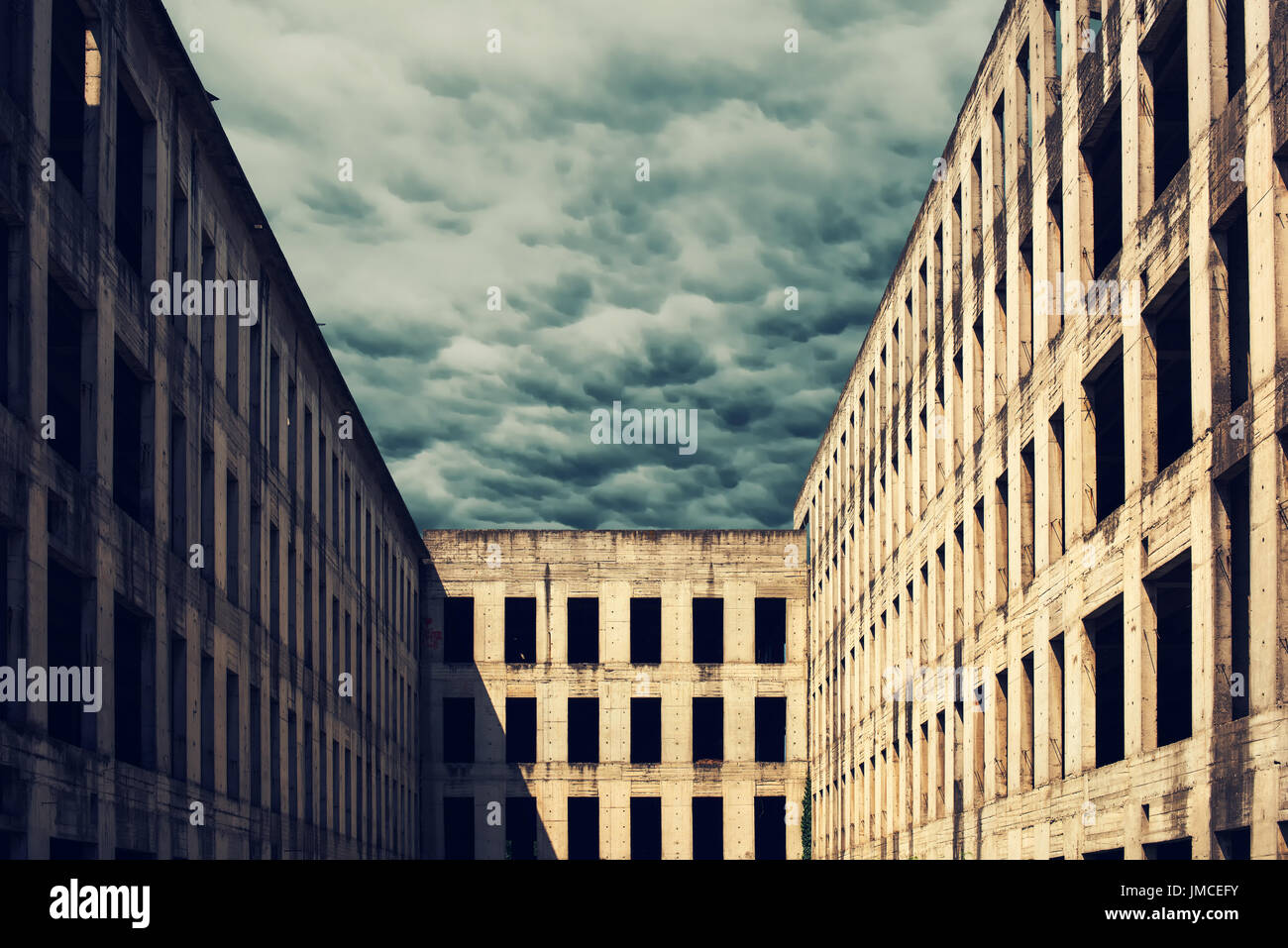 La façade de l'immeuble en béton abandonnés non fini avec des nuages orageux dans l'arrière-plan Banque D'Images