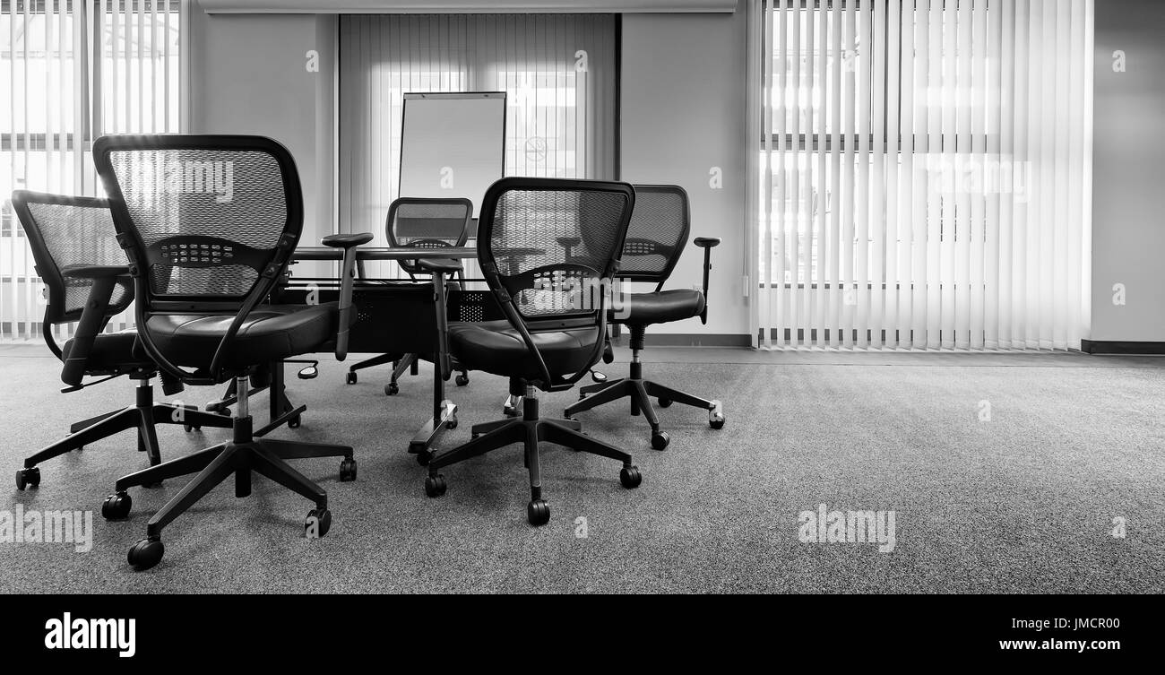 Chaises de bureau ergonomique autour d'une table. Vider la salle de conférence. Stores verticaux. Le noir et blanc Banque D'Images
