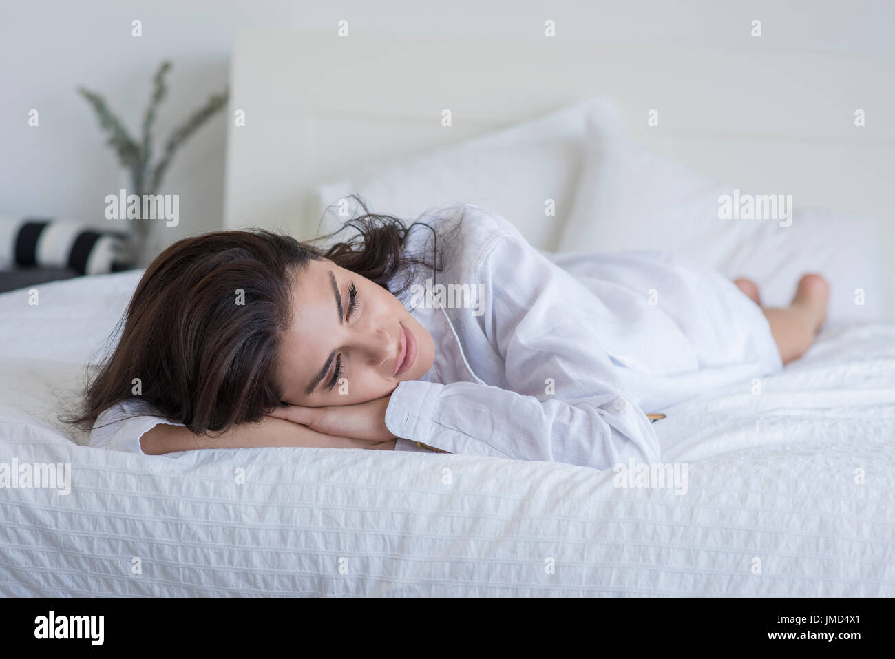 Young woman lying on bed portant une chemise blanche. Banque D'Images