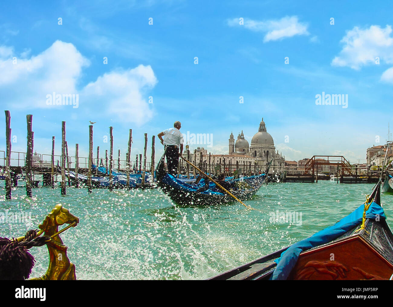Belle journée sur le grand canal prises à partir d'une gondole gondole avec un autre à l'avant avec un gondolier et direction des éclaboussures d'eau et d'une cathédrale Banque D'Images