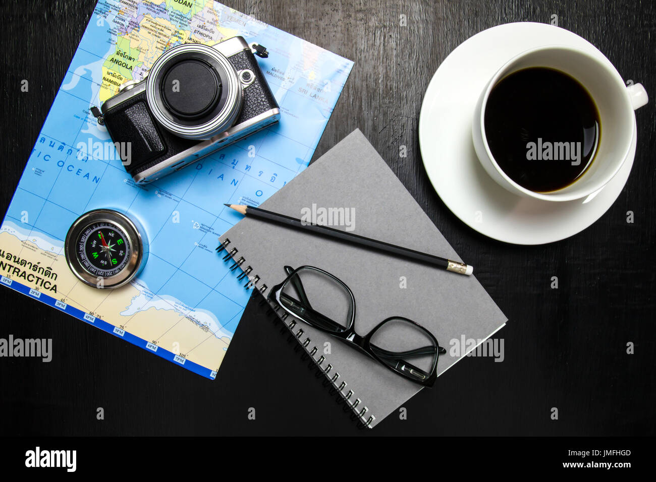 Vue de dessus de l'espace de travail de bureau avec une tasse à café, appareil photo, boussole, carte du monde,ordinateur portable,lunettes ,crayon sur fond de bois Banque D'Images