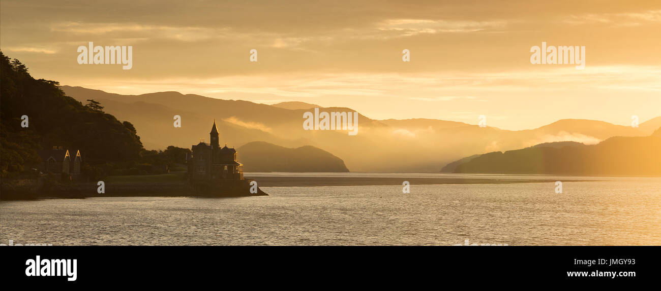 Lever du soleil sur l'estuaire de Mawddach, Snowdonia dans la lumière dorée du soleil s'allume sur les montagnes, la mer et la brume, et le la maison gothique sur les bords Banque D'Images