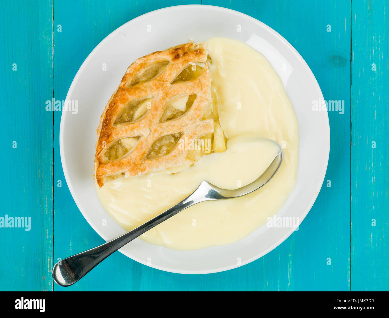 Tarte aux pommes et crème anglaise dessert against a blue background Banque D'Images