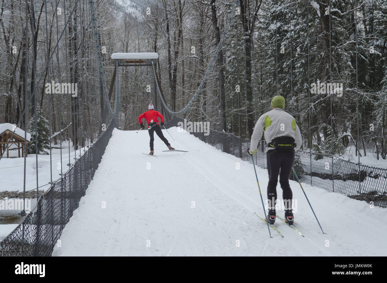 Les skieurs de fond sur le pont suspendu au-dessus de la rivière Methow en hiver, Cascades Nord Washington Banque D'Images
