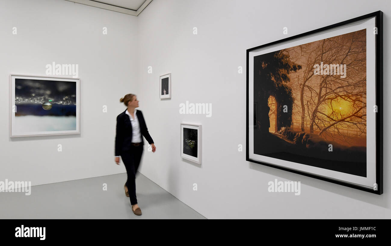 Un employé du musée regarde les photos 'laisse-moi' (2010), 'Schafe II' (2009) et 'CachZe' (2010) (l-r) à l'Sprengel Museum de Hanovre, Allemagne, 27 juillet 2017. Les photos font partie de 120 photographies de photographe allemand Sascha Weidner qui sont affichés dans l'exposition 'Tout est connecté d'une certaine manière", ouvert du 29 juillet jusqu'au 19 novembre 2017. Photo : Holger Hollemann/dpa Banque D'Images