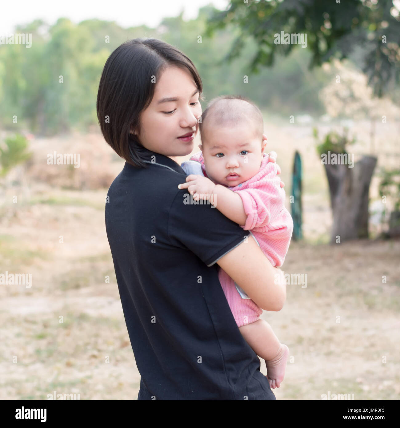 Portrait of young mother holding her little baby looking at camera et montrant son doigt du milieu Banque D'Images