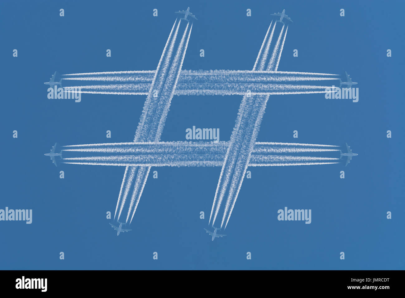 Quatre avions laisser trainées dans la forme du signe #  hashtag contre un ciel bleu foncé. Banque D'Images