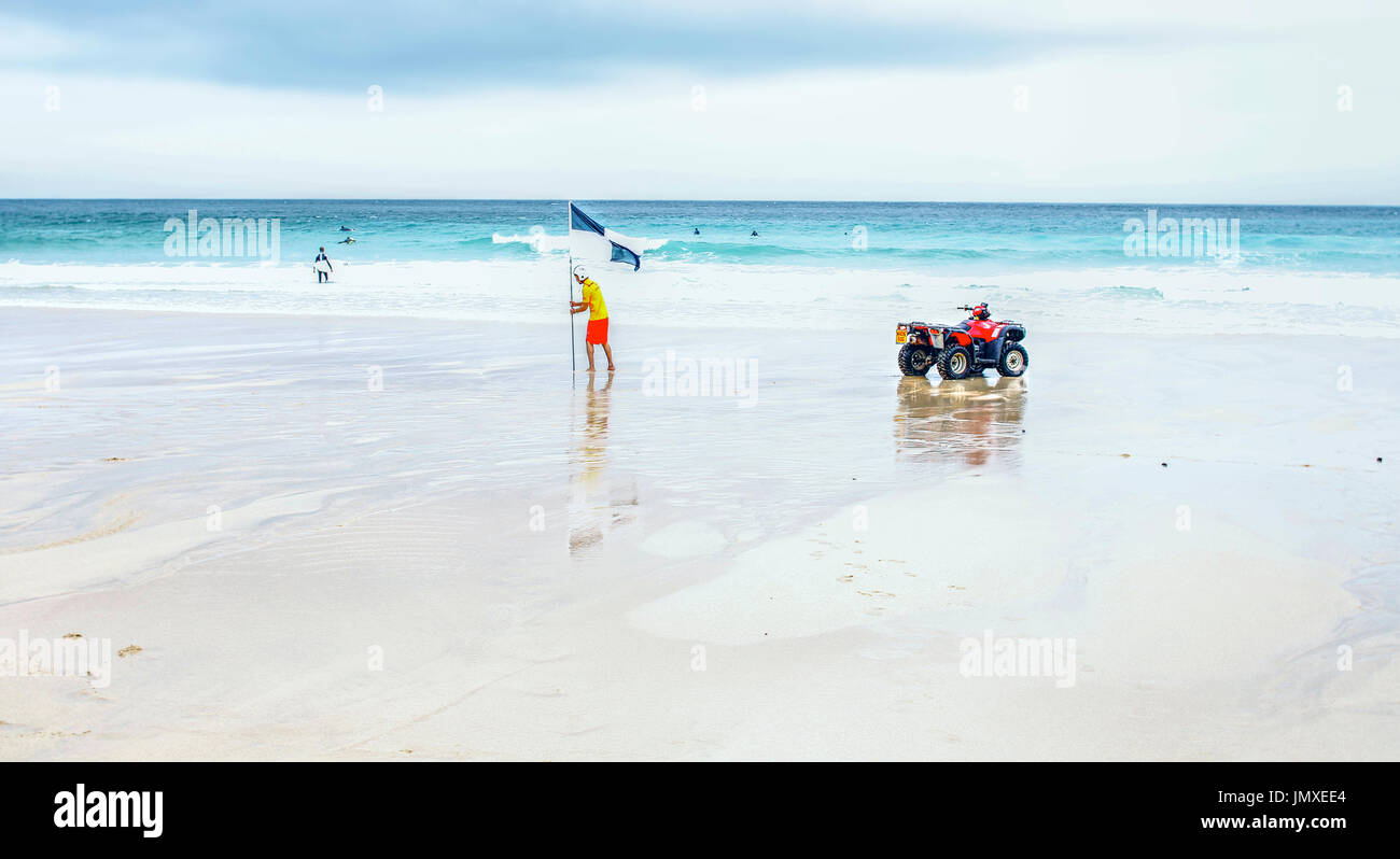 Un sauveteur sur la plage de St Ives, Cornwall définissant un drapeau de surf Banque D'Images
