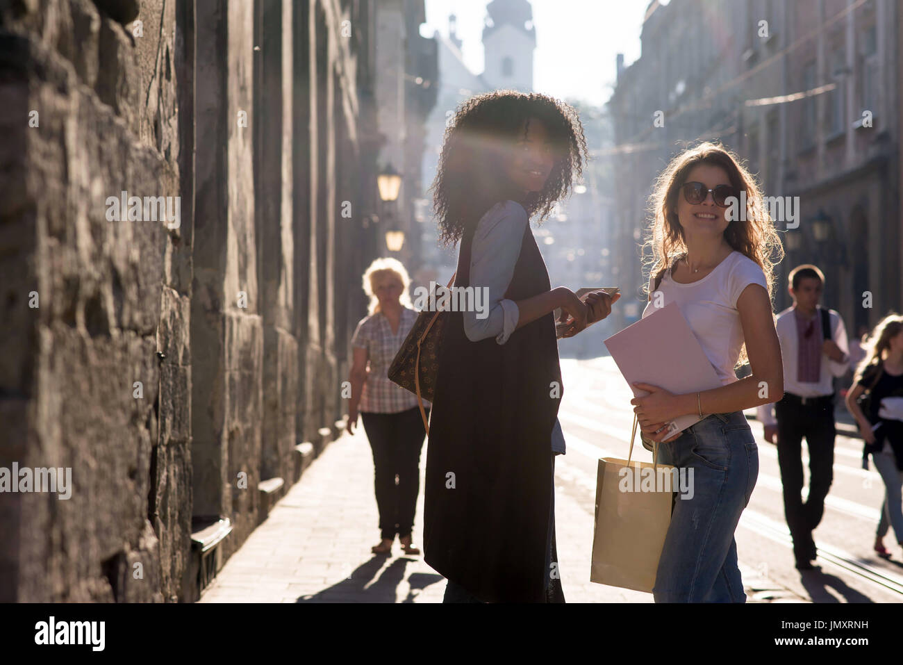 Deux belles filles marcher autour de la ville avec les sacs et les boks. Une fille est african american Banque D'Images