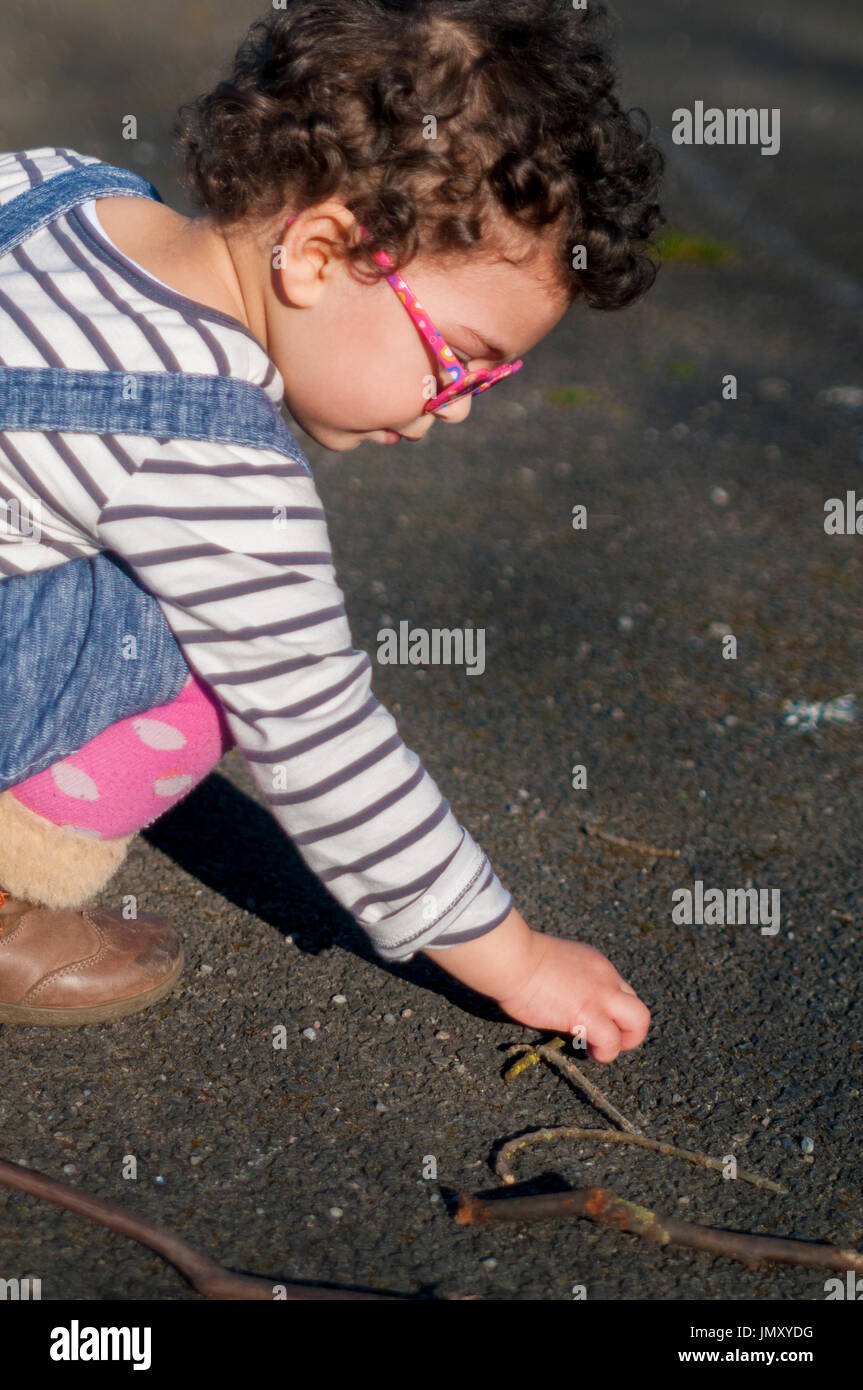 Portrait d'une petite fille qui ramasse les petits bâtonnets de bois. Banque D'Images