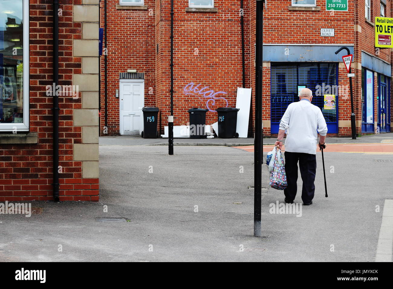 Personnes âgées man walking down street with shopping Banque D'Images