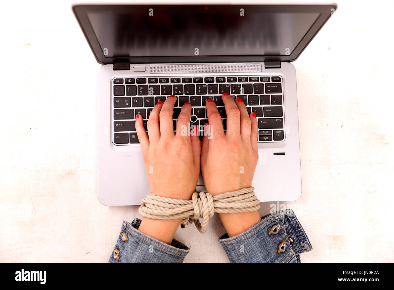 L'esclavage moderne concept. Woman's main liée à travailler sur un ordinateur au travail Banque D'Images