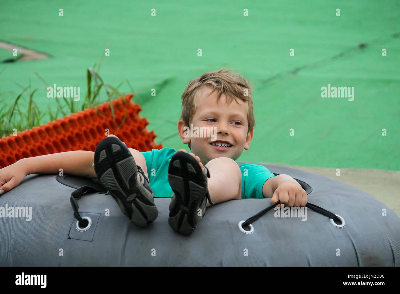 Smiling boy glisse vers le bas dans l'anneau gonflable Banque D'Images