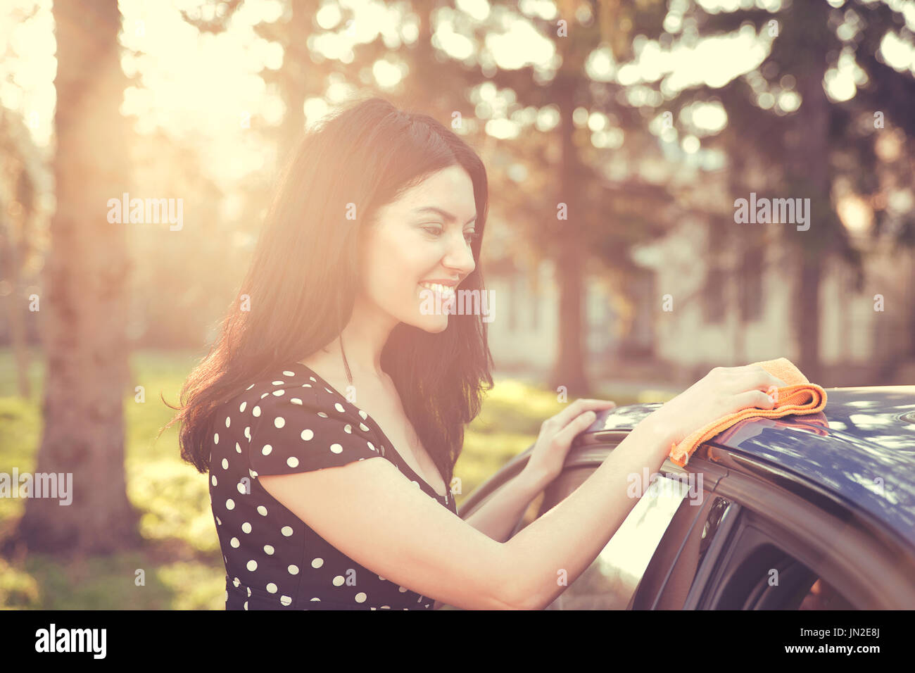 Jeune femme d'essuyage à sec sa voiture avec chiffon microfibre après lavage, nettoyant auto. Transports - le libre-service, concept de soins. Banque D'Images