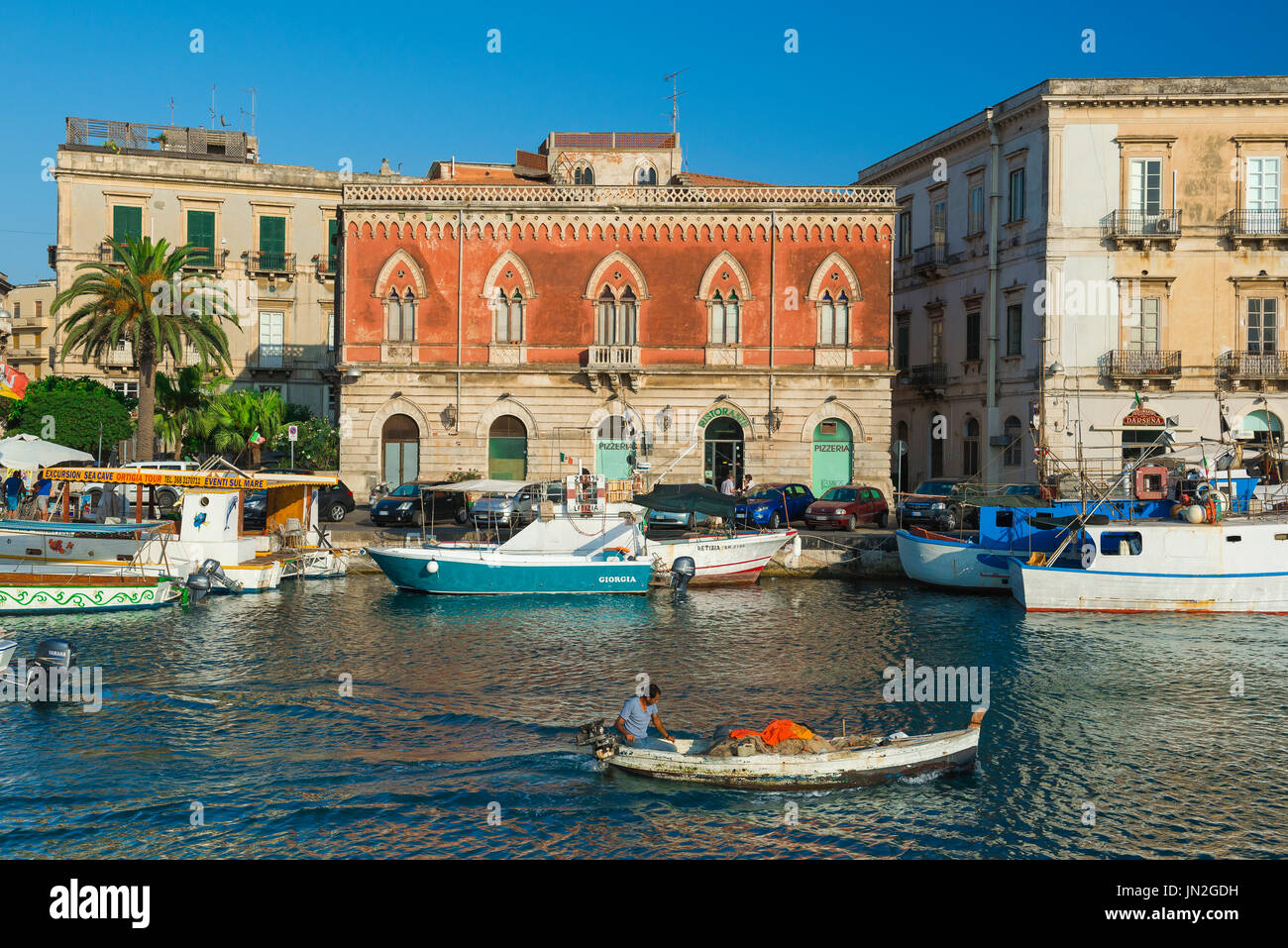Ville de Sicile, vue d'un pêcheur qui dirige son bateau dans le pittoresque canal de Darsena entre le port de Syracuse et l'île historique d'Ortigia, la Sicile Banque D'Images