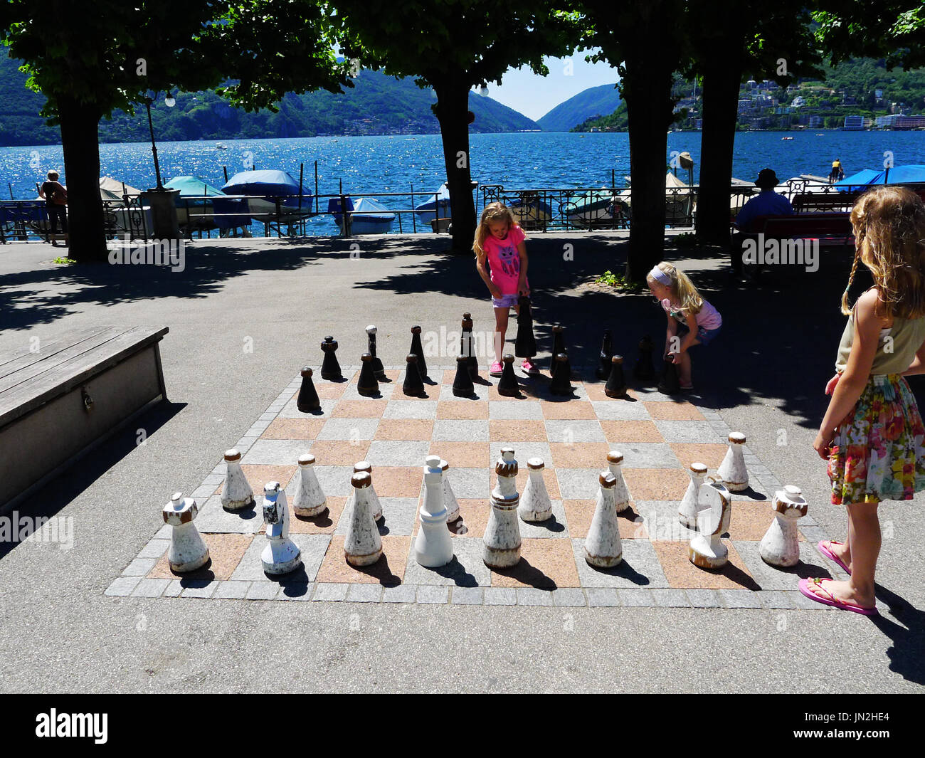Enfants Enfants famille filles jouant avec un échiquier géant au bord du lac de Lugano en Italie Banque D'Images
