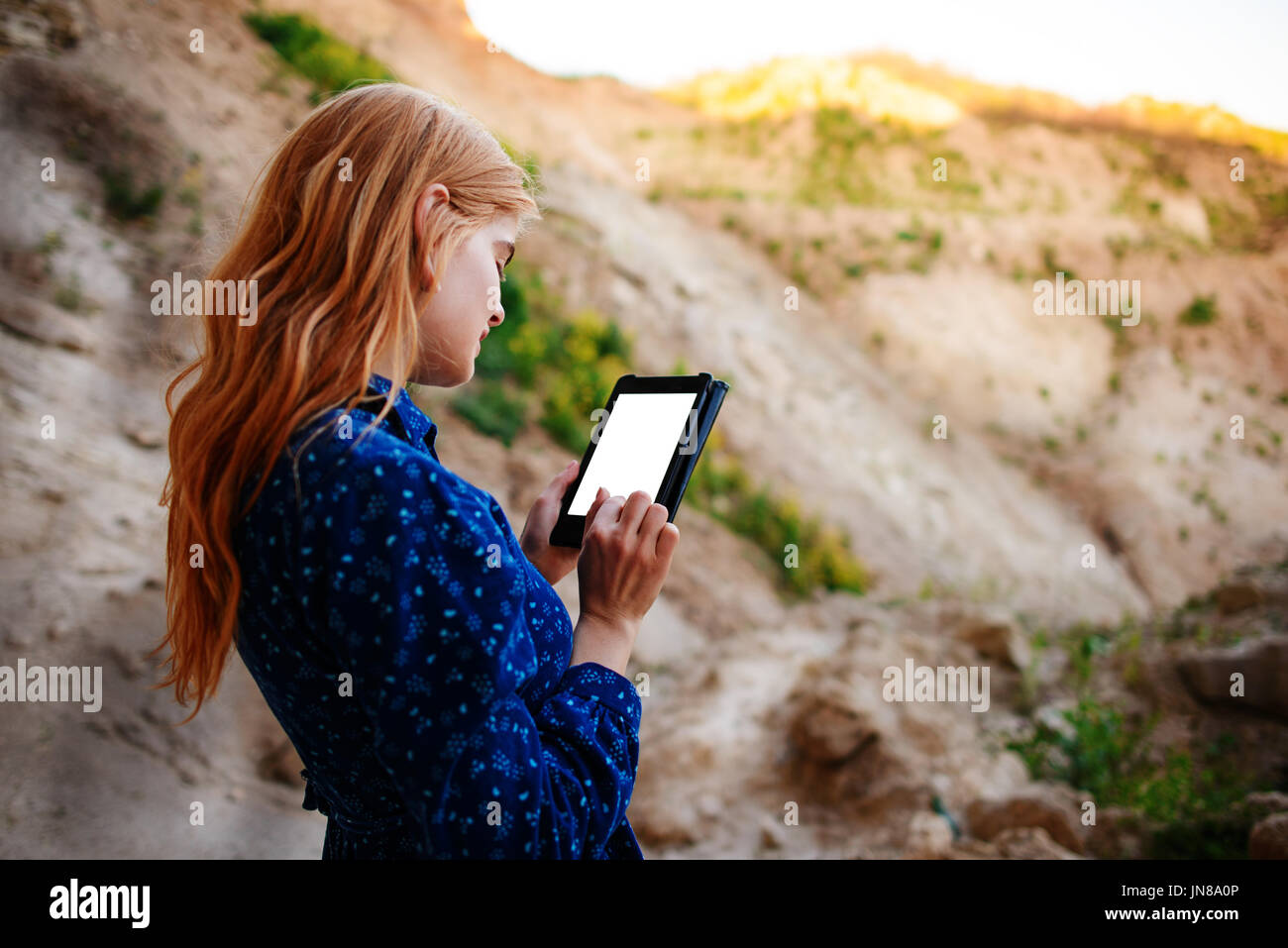 Femme regardant l'écran d'une tablette sur le fond d'une carrière de sable. Banque D'Images