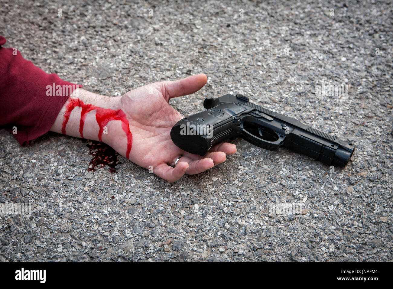 La main de l'homme allongé sur le sol après le suicide avec une arme à feu Banque D'Images