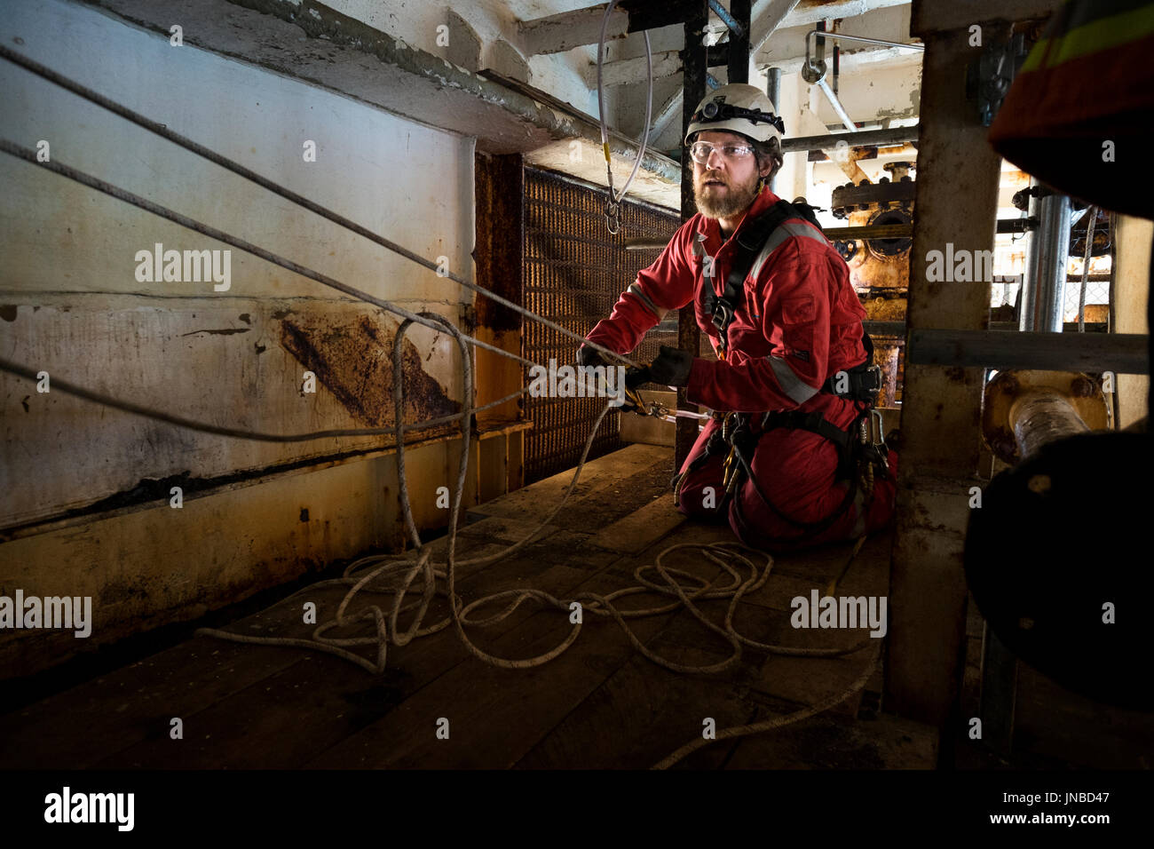 Une corde industriel technicien d'accès mise en place d'un système de transport recsue, vêtu d'une combinaison rouge. crédit : lee ramsden / alamy Banque D'Images