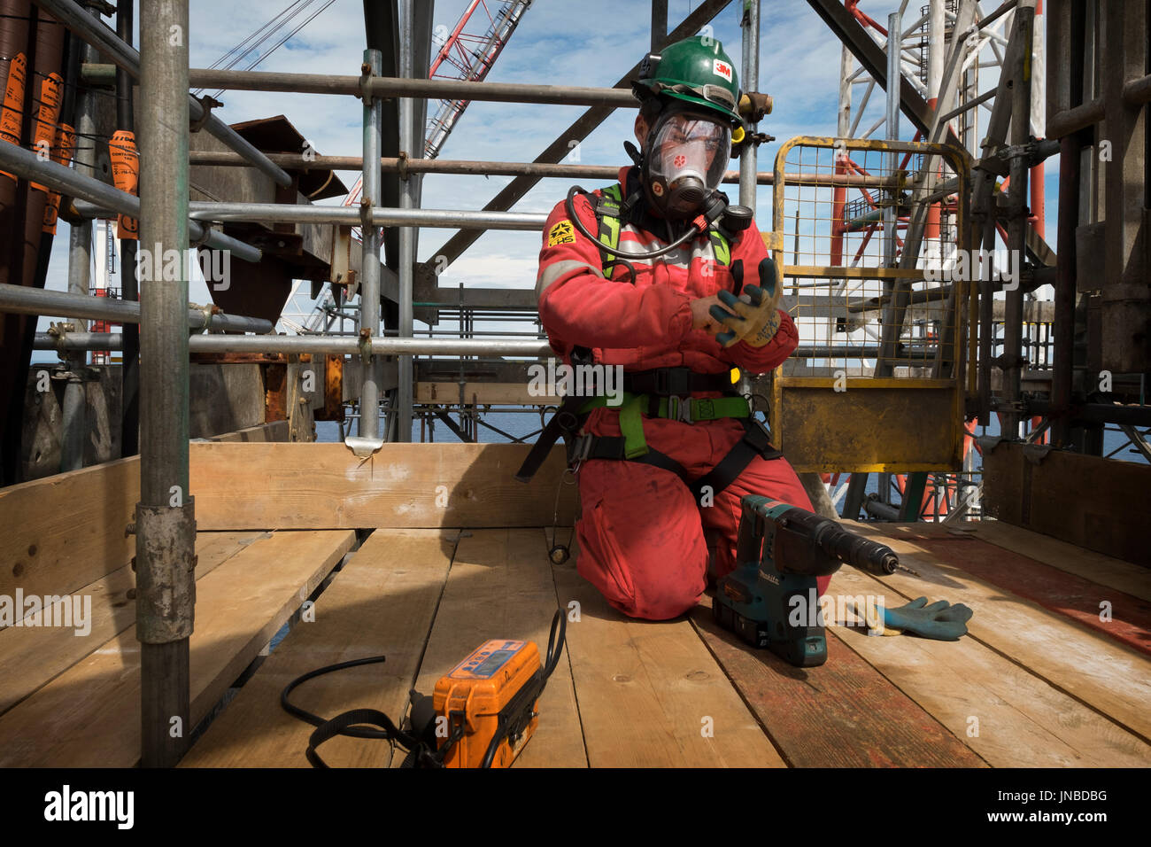 Un travailleur industriel, le port d'appareil respiratoire complet comme sur le point de percer dans un tuyau et effectuer un test de gaz. crédit : lee ramsden / alamy Banque D'Images