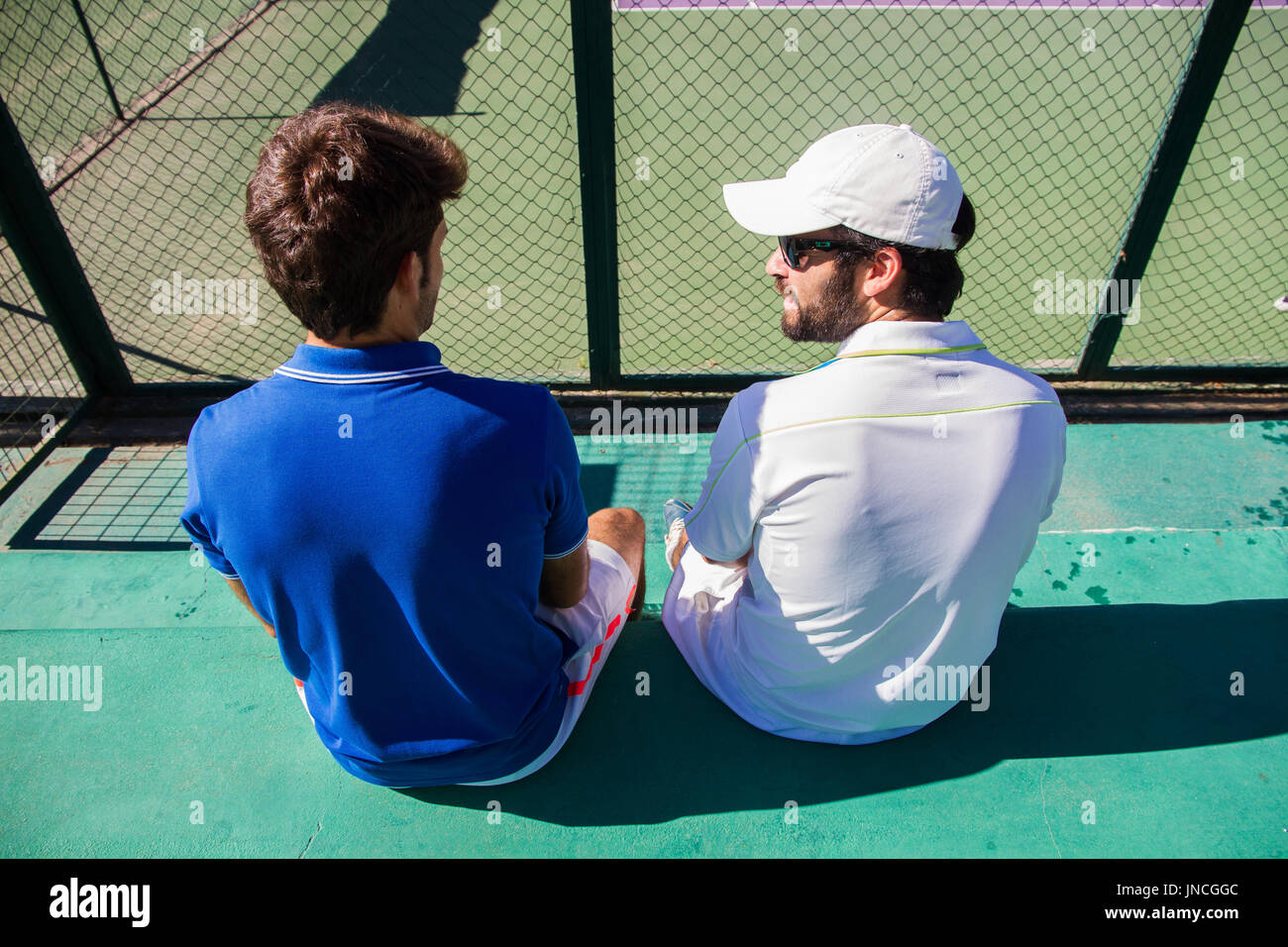 Deux joueurs professionnels se reposant après une partie de tennis. Ils sont amis et sont assis en appui pour le jeu. Ils sont heureux et rire. Banque D'Images