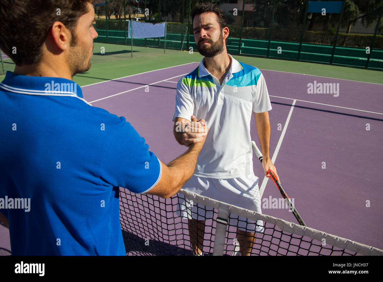 Deux hommes, joueurs professionnels de tennis se serrent la main avant et  après le match de tennis. L'un d'elles a le visage de la colère Photo Stock  - Alamy