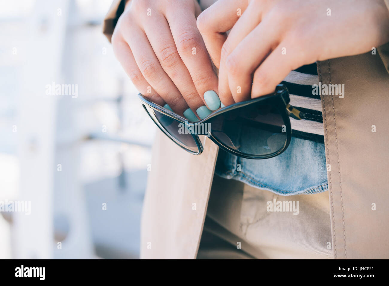 Femme dans un manteau beige détient des lunettes de soleil dans ses mains, close-up Banque D'Images