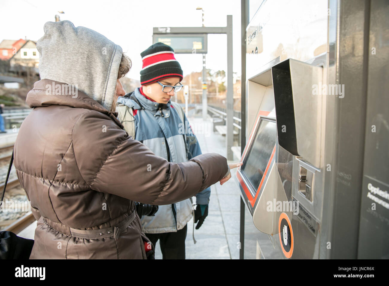 Garçon et femme acheter des billets à la billetterie à l'arrêt de tramway à Bergen, Norvège Banque D'Images