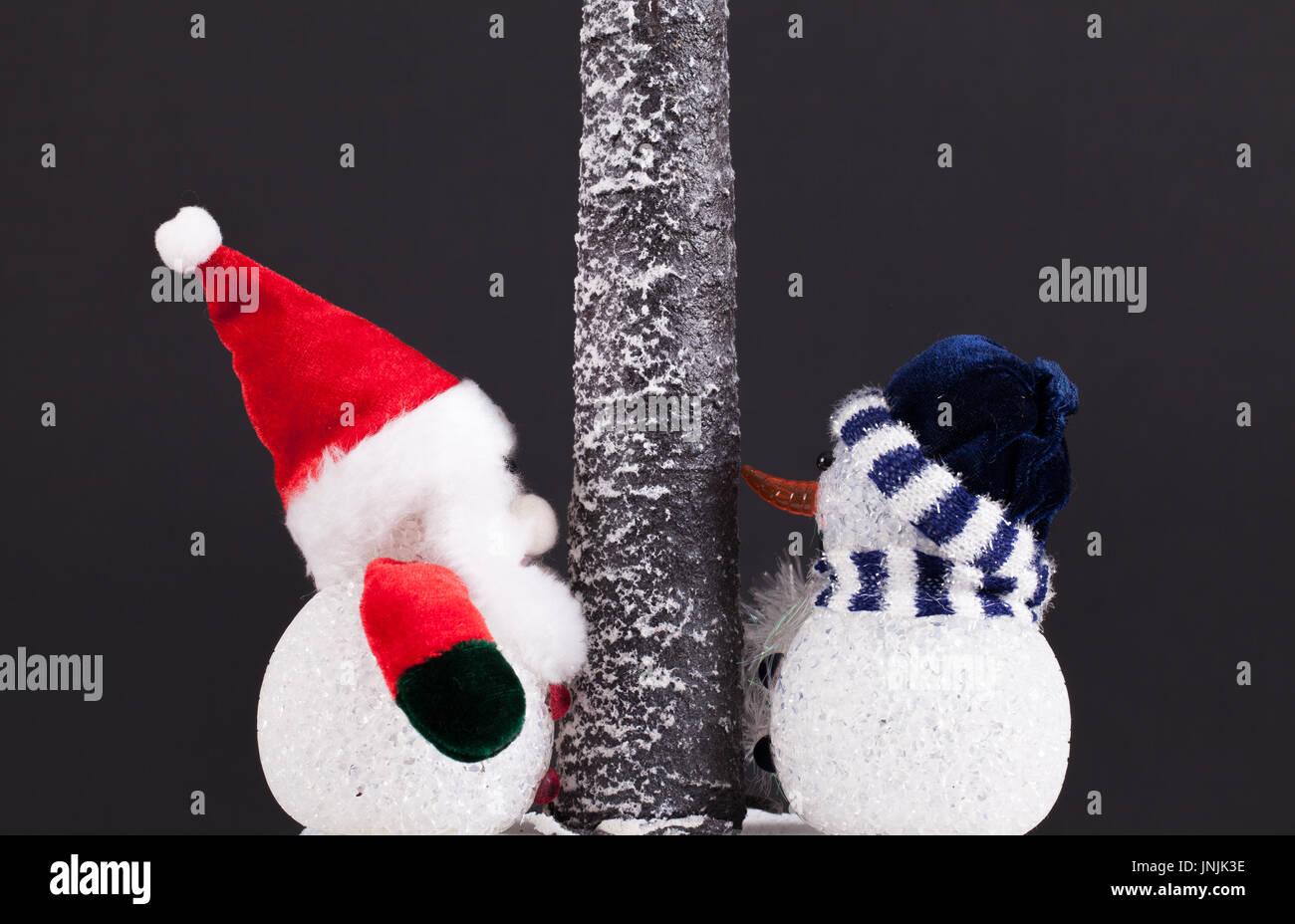 Père noël et bonhomme de neige jouet sous un arbre. scène festive sur fond noir Banque D'Images