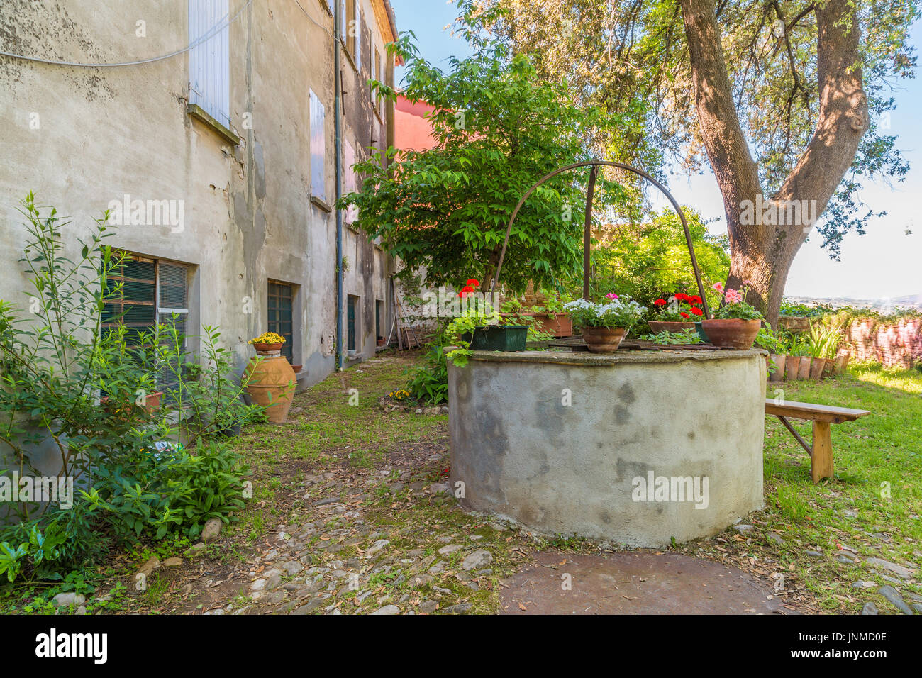 La sérénité de la cour d'une ancienne ferme avec ancien puits et de fleurs, en Romagne, Italie Banque D'Images