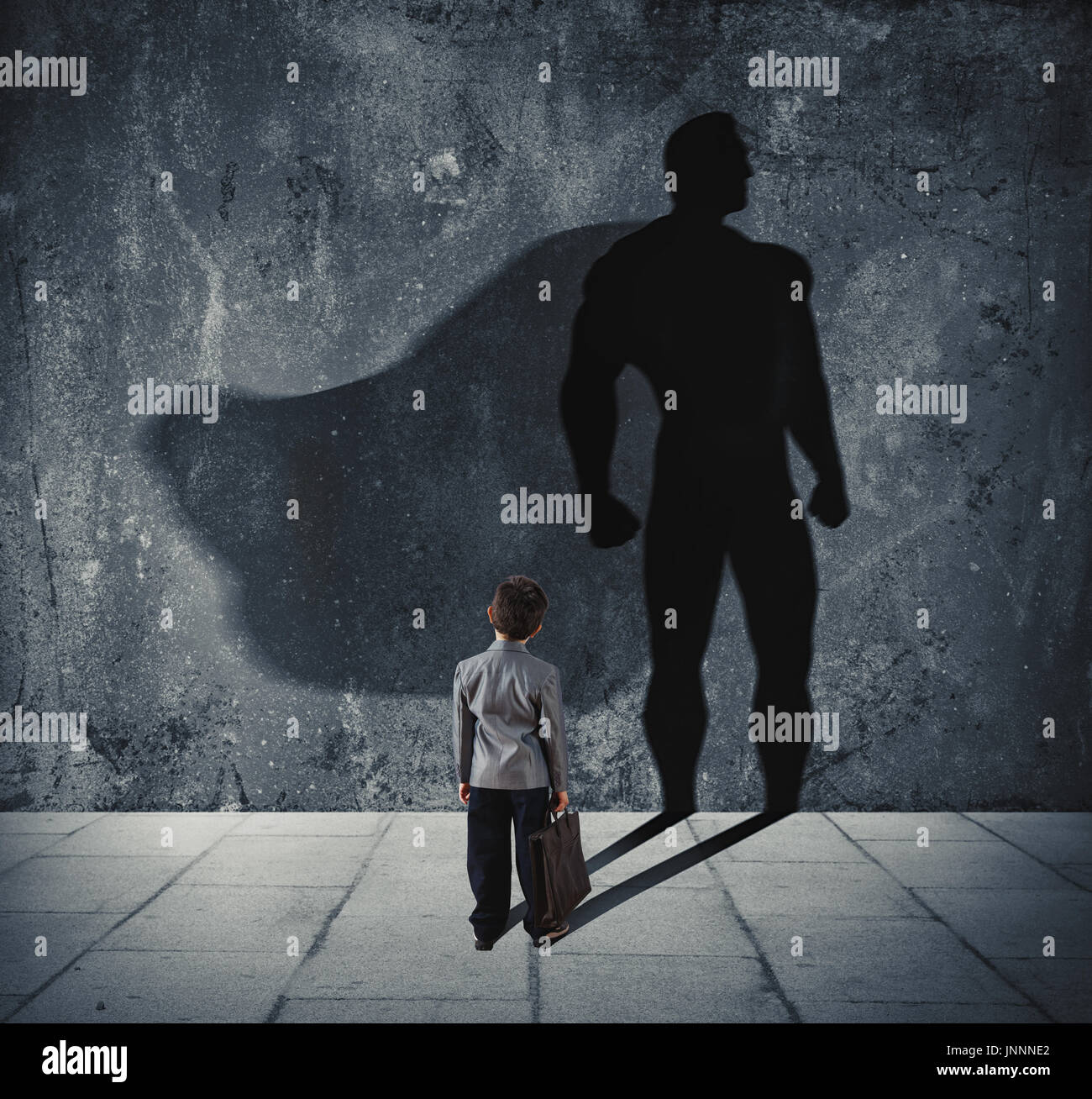 Jeune homme avec son ombre de super héros sur le mur. Concept de petit homme puissant Banque D'Images