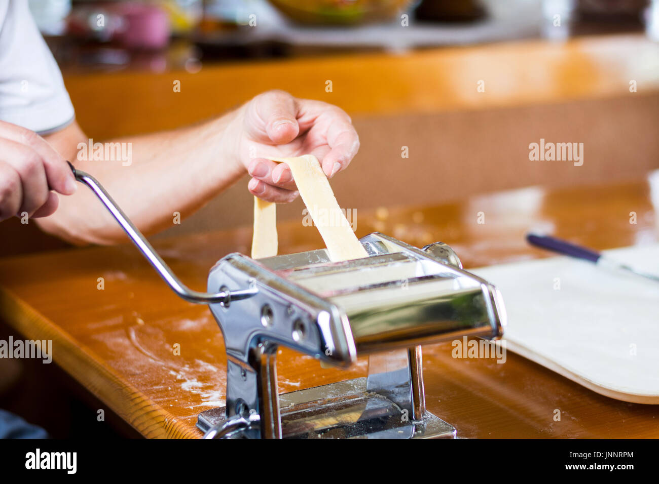 L'homme faisant des pâtes faites à la maison avec une machine Banque D'Images
