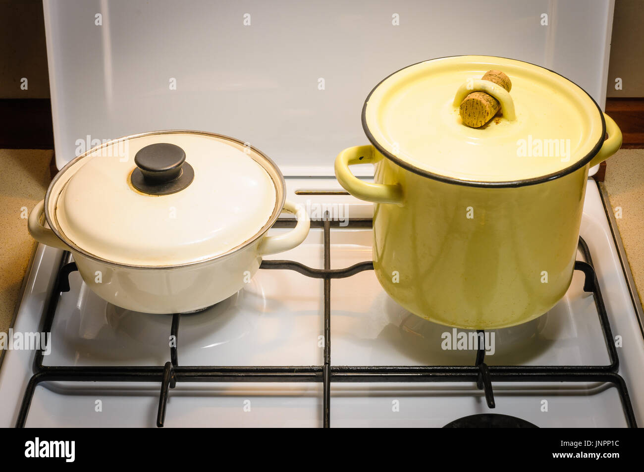Un jaune et un pot blanc sur la cuisinière à gaz dans la cuisine Banque D'Images